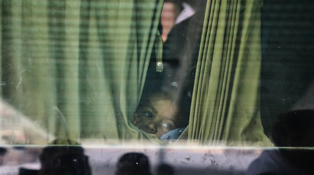 طفل فلسطيني مريض ينظر من نافذة سيارة مع مرضى آخرين في خان يونس خلال توجههم إلى معبر رفح يوم الاثنين (أ.ب)