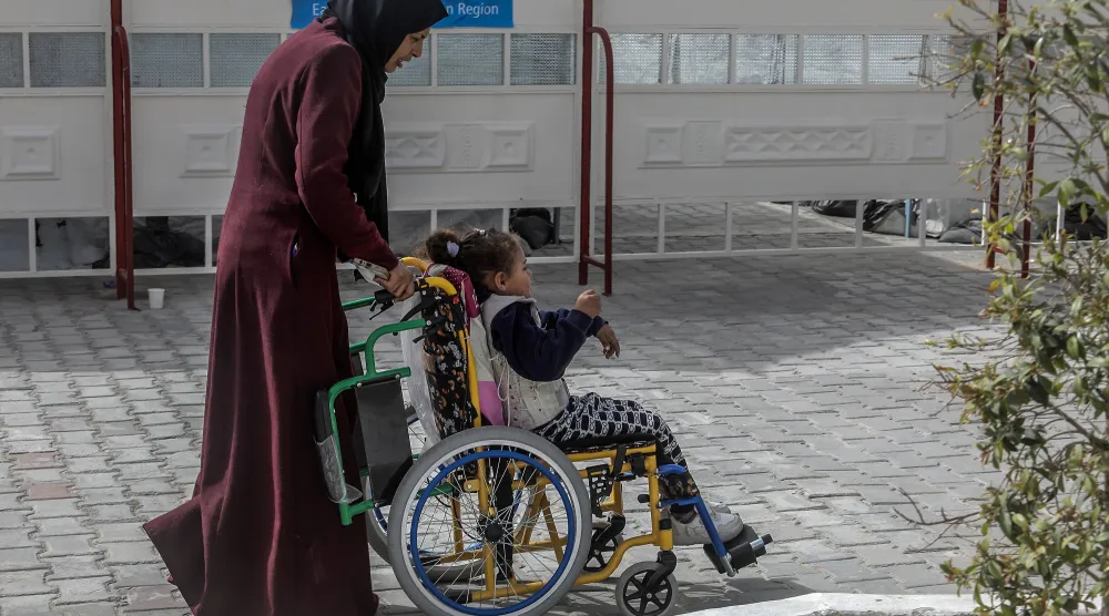 فلسطينية وطفلتها المصابة في خان يونس في انتظار الخروج من قطاع غزة (د.ب.أ)