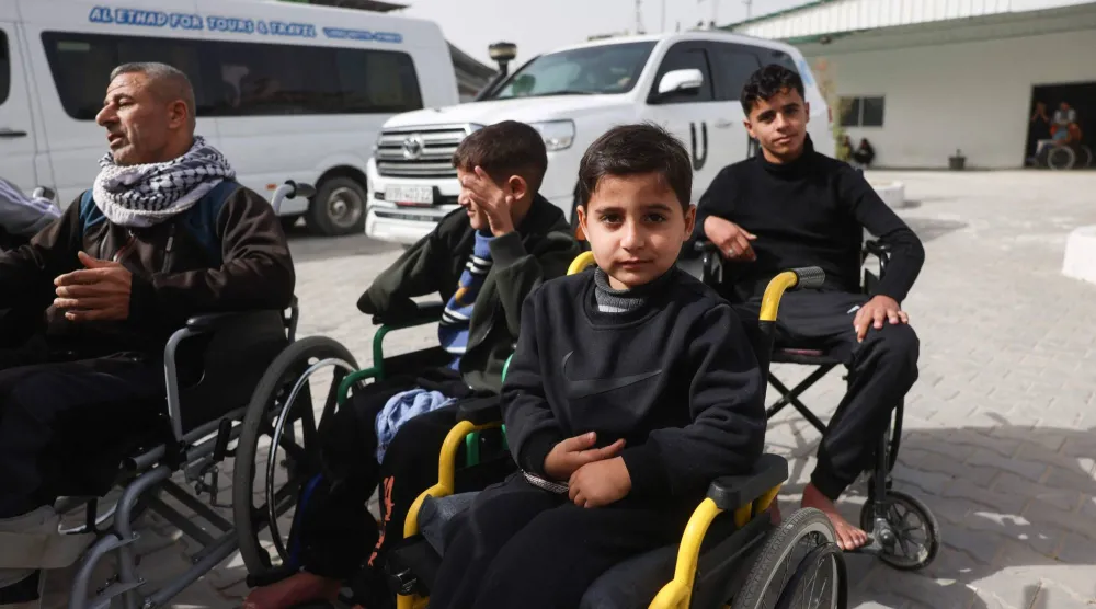 مرضى فلسطينيون يجلسون على كراسي متحركة في ساحة مستشفى «الهلال الأحمر» بخان يونس منتظرين إجلاءهم من قطاع غزة عبر معبر رفح الحدودي مع مصر لتلقي العلاج في الخارج (أ.ف.ب)