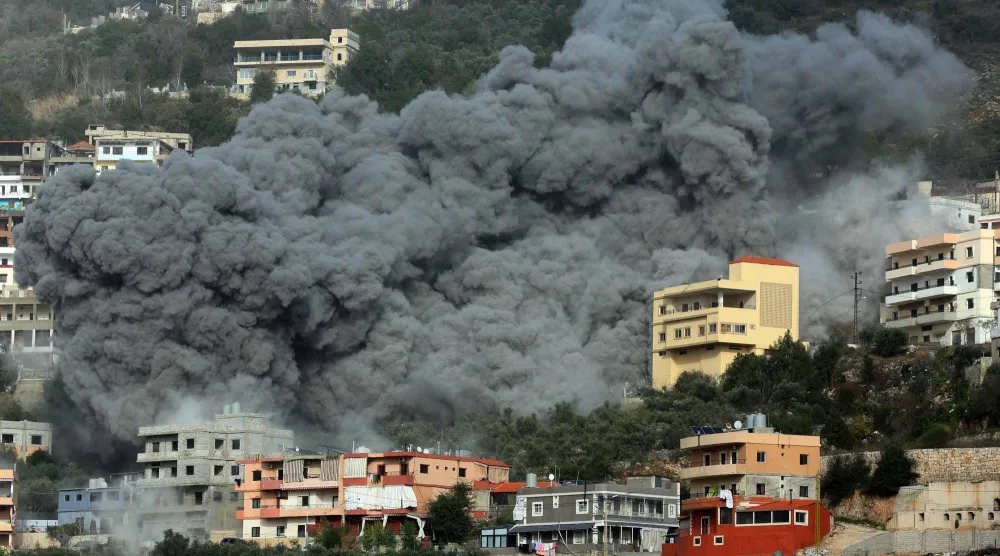 دخان كثيف يتصاعد من مبنى استهدفته غارة إسرائيلية في قرية عين قانا بالجنوب اللبناني أمس (أ.ف.ب)