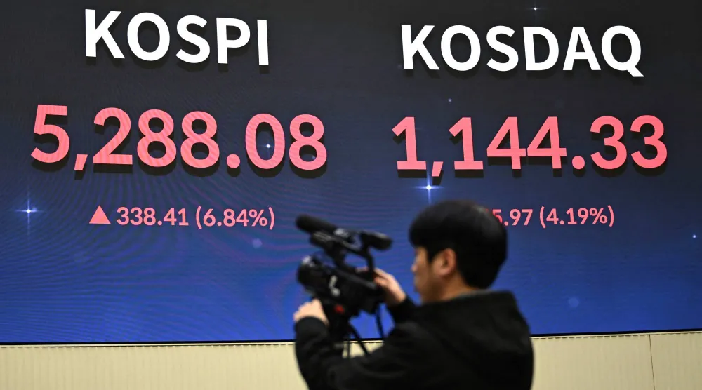 مصوّر تلفزيوني أمام شاشة إلكترونية تعرض مؤشر «كوسبي» ومؤشر «كوسداك» في بورصة كوريا في سيول (أ.ف.ب)