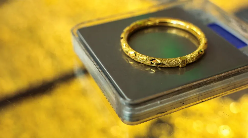 بائع يزن سواراً ذهبياً للبيع لعميل بمتجر ذهب في بانكوك بتايلاند (رويترز)