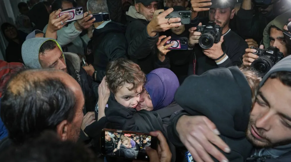 نجاة روبائي (وسط) تعانق أحد أحفادها بعد وصولهم مع والدتهم ضمن مجموعة تضم نحو اثني عشر فلسطينياً سُمح لهم بدخول غزة عقب إعادة فتح معبر رفح الحدودي (أ.ب)