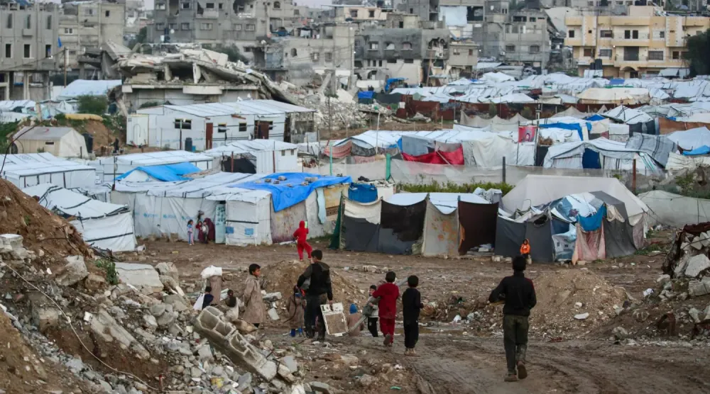 Gazze Şeridi'nin merkezindeki Bureyc mülteci kampında çocuklar çadırların ve geçici barınakların önünden geçiyor, (AFP)
