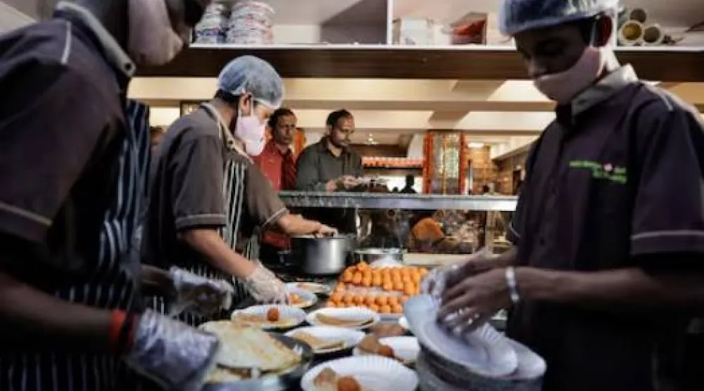 يقدّم الموظفون الطعام في أحد المطاعم بمدينة بنغالورو بولاية كارناتاكا (رويترز)