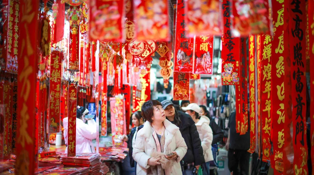 صينيون يشاهدون عرضا للمصابيح والزينات الخاصة بالعام الجديد في سوق بشمال شرقي البلاد (أ.ف.ب)