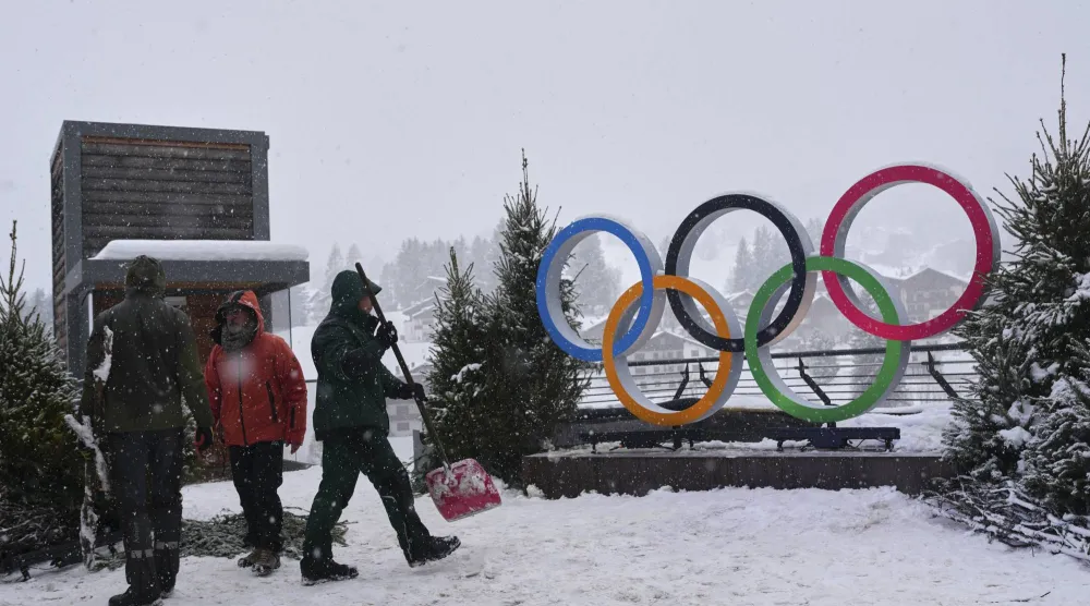 أشخاص يعملون بالقرب من الحلقات الأولمبية المعروضة استعداداً لدورة الألعاب الأولمبية الشتوية 2026 (أ.ب)