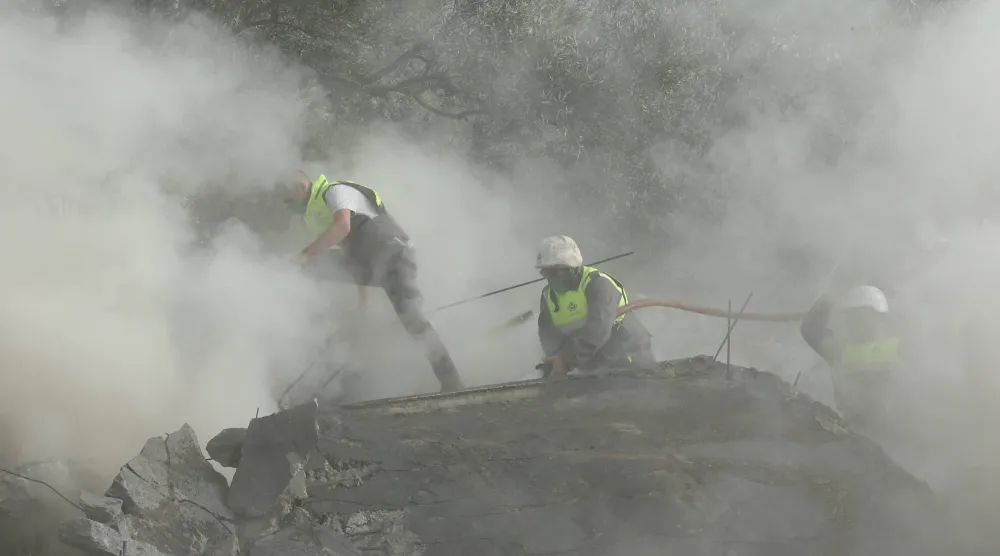 عناصر الدفاع المدني يكافحون النيران في موقع غارة جوية إسرائيلية استهدفت مبنى في قرية عين قانا جنوب لبنان (أ.ف.ب) 