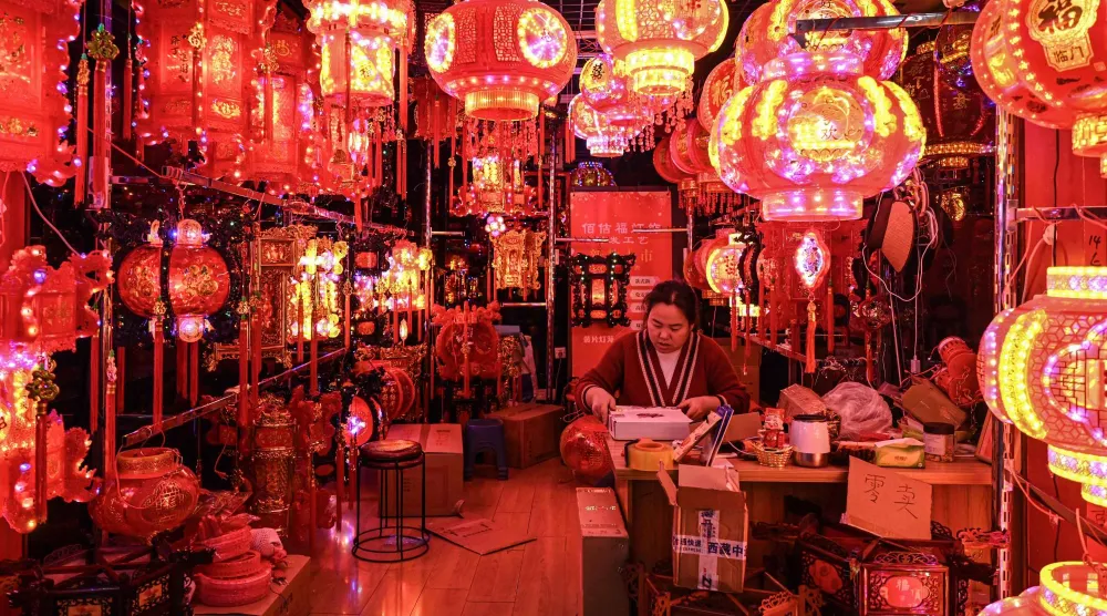 بائع ينتظر الزبائن في كشك لبيع الفوانيس قبل حلول السنة القمرية الجديدة للحصان (أ.ف.ب)