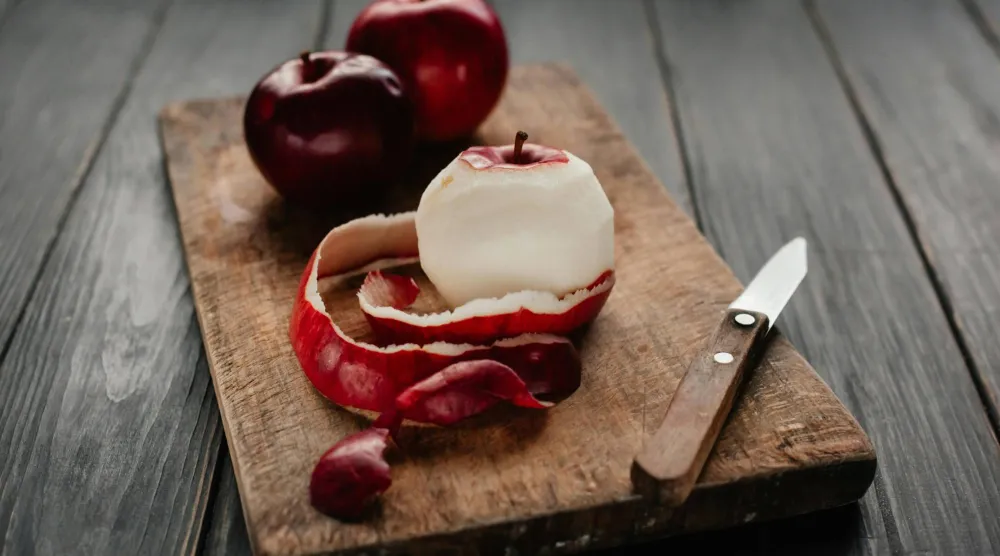 شخص يقوم بتقشير التفاح الأحمر (بيكسلز)