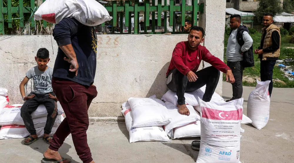 نازحون فلسطينيون تسلموا أكياس طحين من مركز تابع لـ«الأونروا» بمدينة غزة - 1 أبريل 2025 (أ.ف.ب)