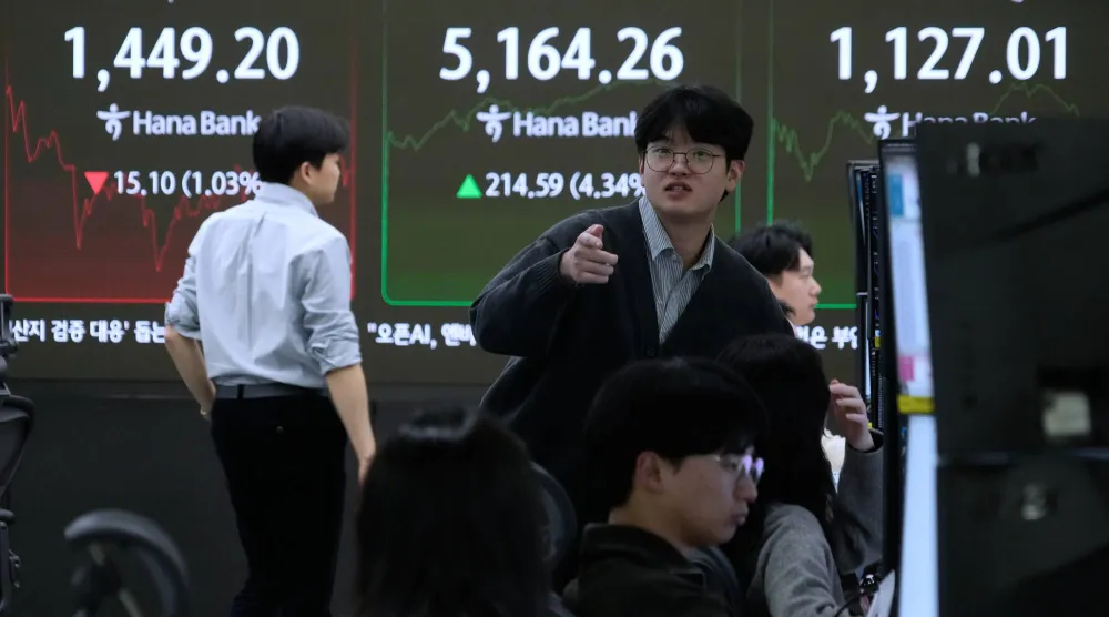 متداولو العملات أمام شاشة تعرض مؤشر كوسبي وسعر صرف الدولار مقابل الوون في مقر بنك هانا بسيول (أ.ب)