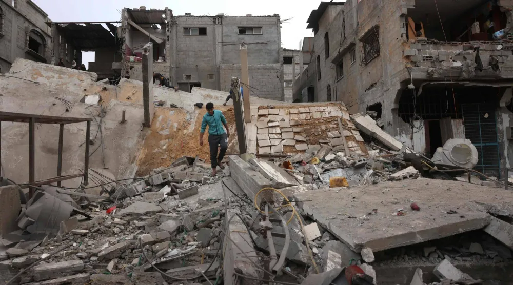 فلسطيني يسير فوق دمار مبنى من 5 طبقات دمرته غارة إسرائيلية في خان يونس جنوب قطاع غزة الجمعة (أ.ف.ب)