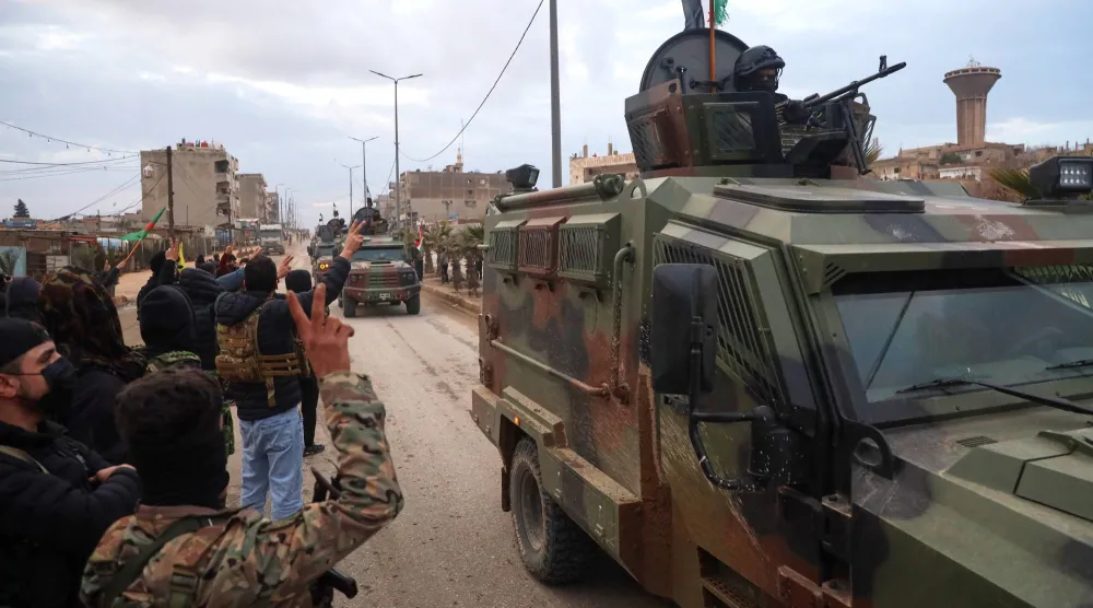 مقاتلون من «قسد» يرحبون بقافلة تابعة لوزارة الداخلية السورية إلى القامشلي في شمال شرقي سوريا (أ.ب)