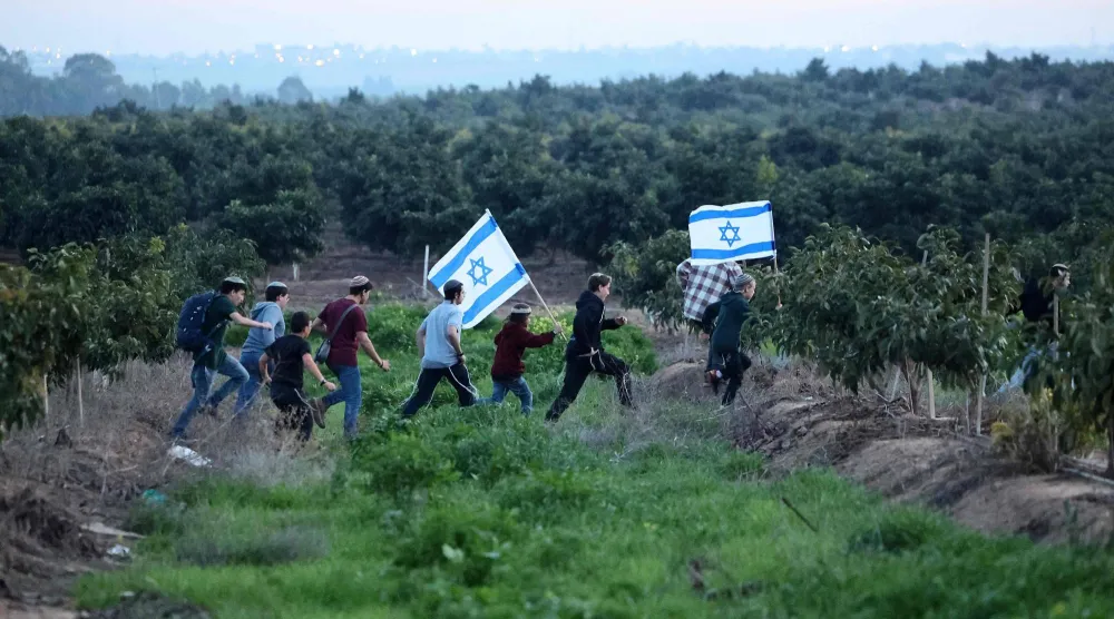 مستوطنون إسرائيليون يسيرون باتجاه الحدود مع غزة الخميس (أ.ف.ب)