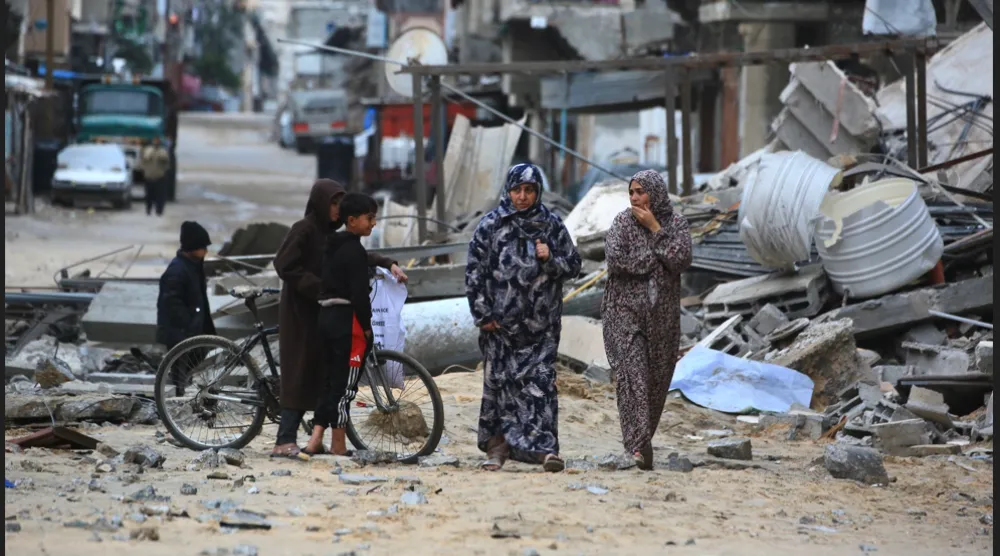امرأة فلسطينية نازحة تسير بين الأنقاض والحطام في خان يونس جنوب قطاع غزة (أ.ف.ب)