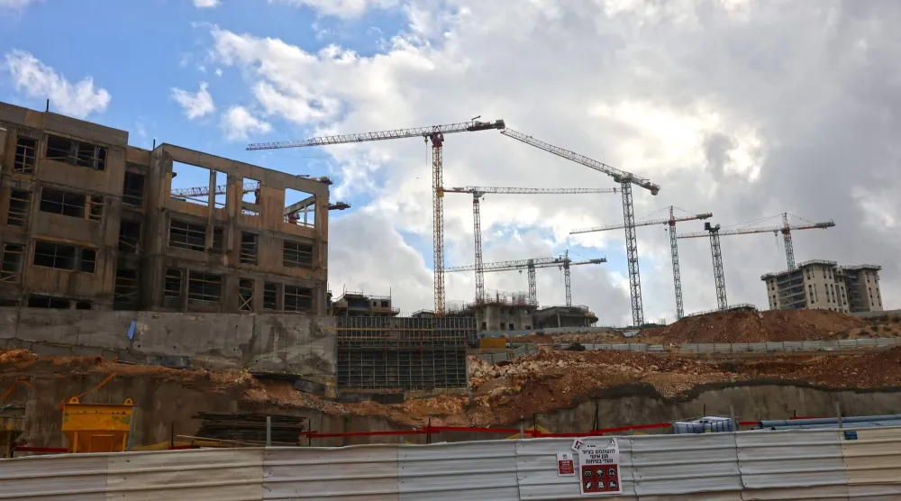 رافعات بناء شاهقة تعلو موقع بناء في جفعات هاماتوس إحدى المستوطنات الإسرائيلية في القدس الشرقية المحتلة (أ.ف.ب)