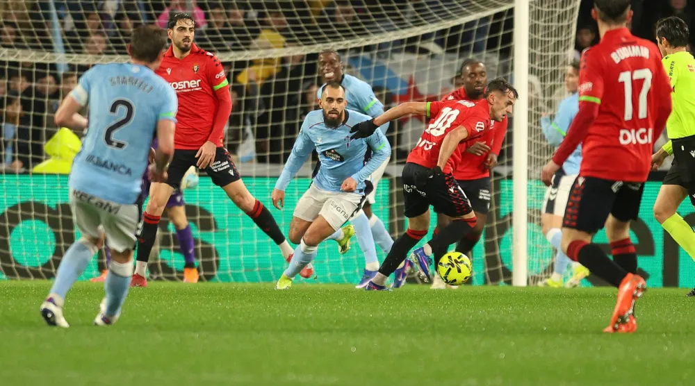 لاعب وسط أوساسونا إيمار أوروز يلعب الكرة تحت ضغط من مهاجم سيلتا فيغو بورخا إيغليسياس (إ.ب.أ).