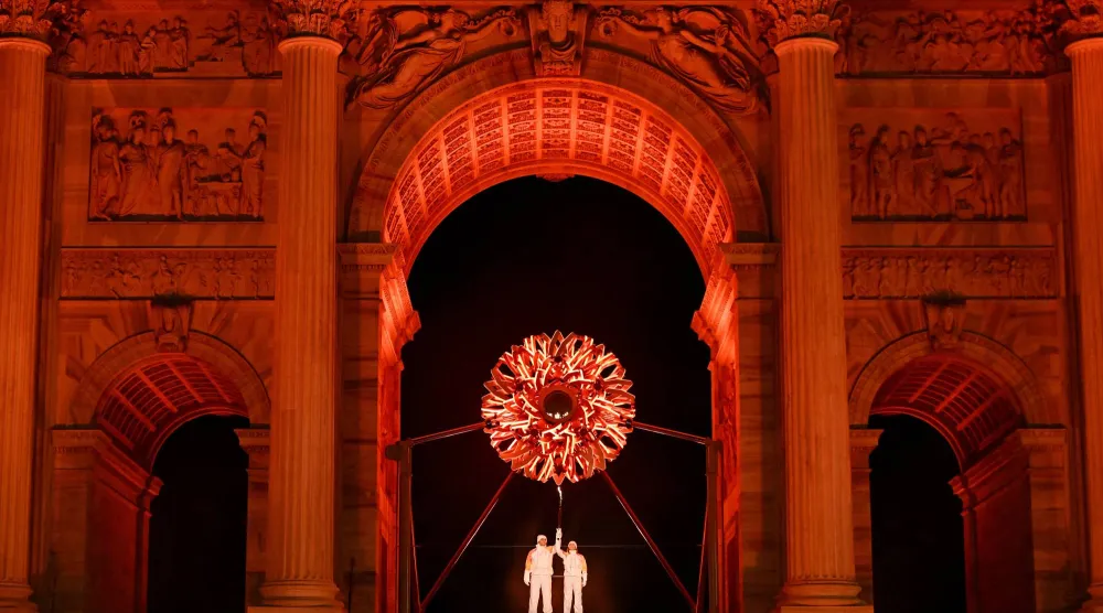 ألبرتو تومبا وديبورا كومبانيوني يحملان الشعلة الأولمبية تحت المرجل في ساحة «آركو ديلا باتشي» وسط ميلانو (إ.ب.أ).