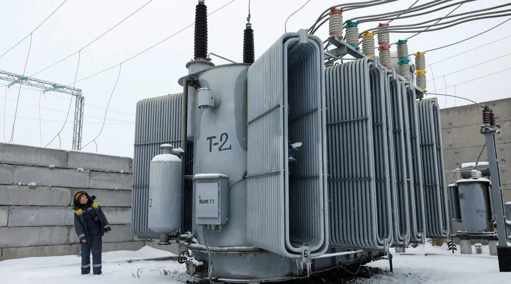 موظف في شركة طاقة يتفقد محولاً كهربائياً بعد أن ألحقت غارات جوية روسية بطائرات مسيرة وصواريخ أضراراً بالغة بالبنية التحتية المدنية الحيوية في كييف (رويترز)