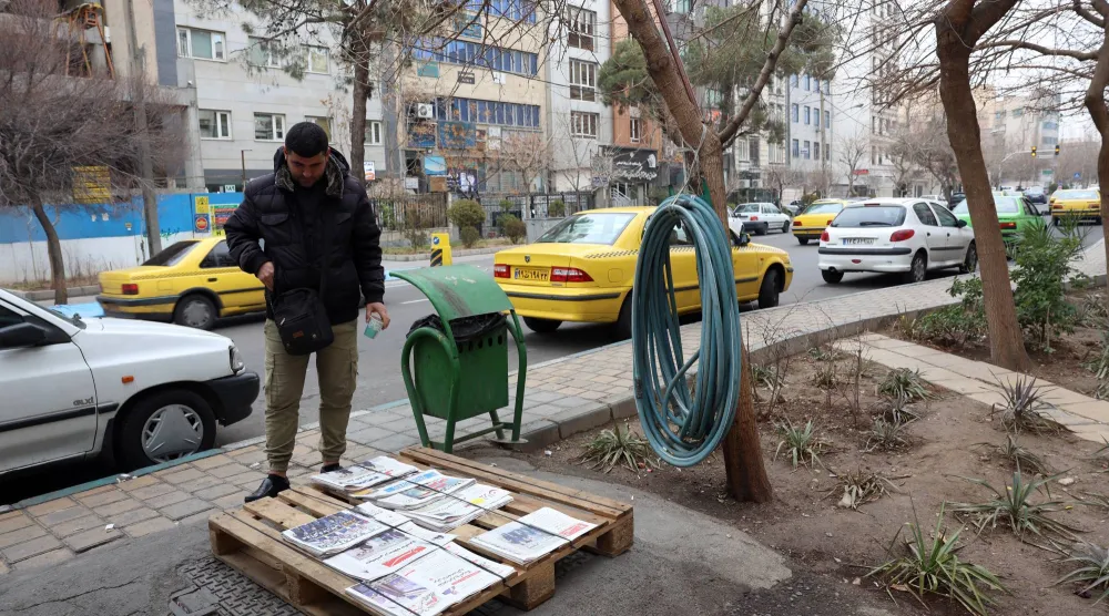 رجل إيراني يطالع العناوين على كشك لبيع الصحف في طهران اليوم (إ.ب.أ)