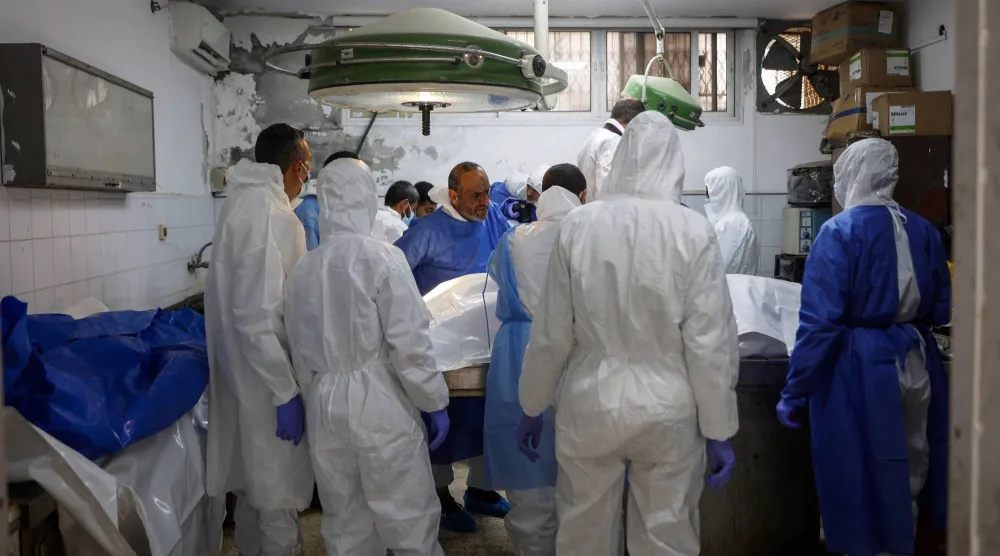 خبراء الطب الشرعي والأطباء يفحصون رفات متوفين من سكان غزة في مستشفى الشفاء (أ.ف.ب)