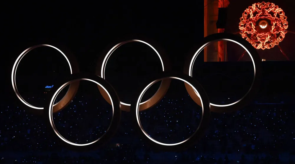 A general view of a screen showing the Olympic flame in the Olympic cauldron designed by Marco Balich, next to the Olympic Rings during the opening ceremony of the Milan Cortina 2026 Winter Olympic Games at the San Siro stadium in Milan, northern Italy, on February 6, 2026. (AFP) 