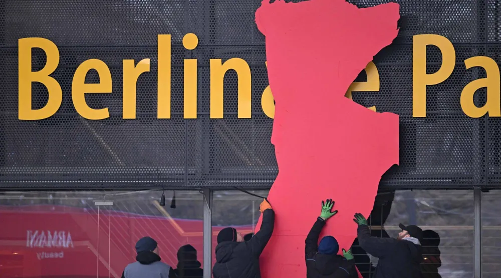 عمال يركّبون دبّ مهرجان برلين السينمائي الدولي على واجهة قصر برلين المقر الرئيسي للمهرجان استعداداً لانطلاق فعالياته (أ.ف.ب)