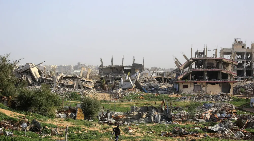 رجل فلسطيني يسير وسط مبانٍ مدمّرة في خان يونس جنوب قطاع غزة (أ.ف.ب)