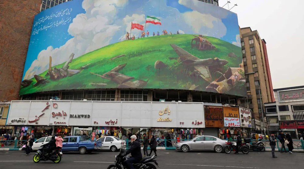 إيرانيون يمرون بجانب لوحة عملاقة مناهضة للولايات المتحدة على مبنى في أحد ميادين طهران ()