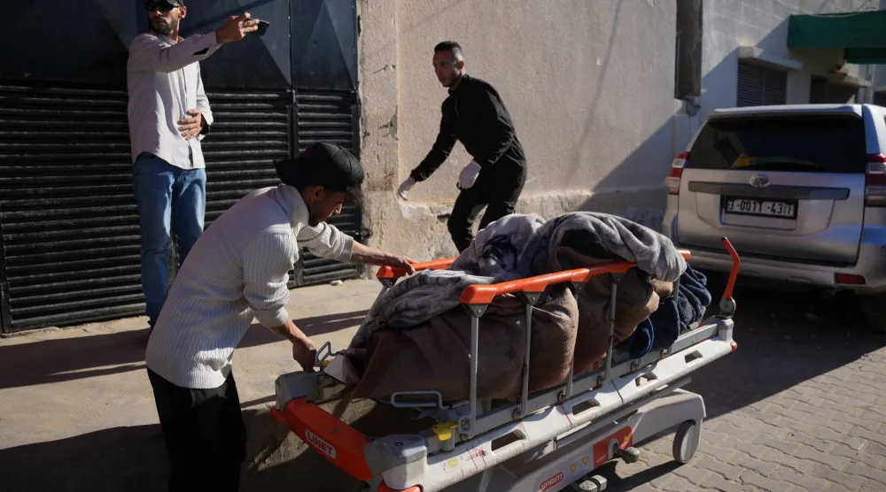 رجل فلسطيني يدفع نقالة تحمل جثتَي شخصين في مستشفى «الأقصى» قُتلا في غارة جوية شنها الجيش الإسرائيلي على مخيم في دير البلح وسط قطاع غزة يوم 4 فبراير 2026 (أ.ب)