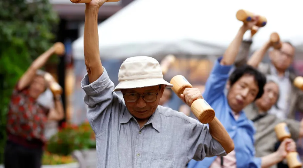 كبار السن ومتوسطو العمر يمارسون تمارين رياضية باستخدام أثقال خشبية خلال فعالية للتوعية الصحية في معبد بحي سوغامو بطوكيو (أرشيفية-رويترز)