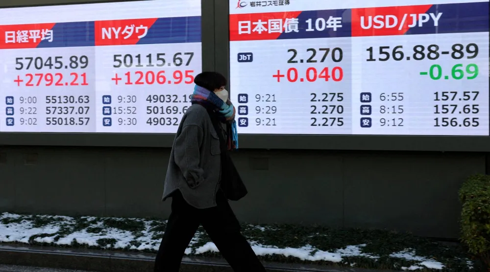سيدة تمر أمام شاشة تعرض حركة الأسهم في وسط طوكيو (رويترز)