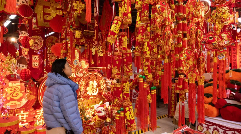 سيدة تشاهد زينات العام الجديد في إحدى الأسواق الشعبية بالعاصمة الصينية بكين (إ.ب.أ)