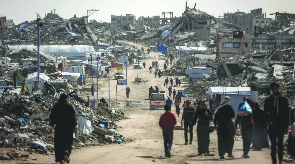 فلسطينيون يمشون وسط المباني المنهارة في مخيم جباليا للاجئين بشمال غزة (أ.ف.ب)