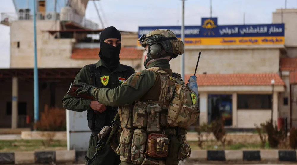 عنصر من الأمن الداخلي مع عنصر من «قسد» يحرسان وفداً من الداخلية السورية وصل إلى مطار القامشلي الدولي شرق سوريا يوم الأحد (أ.ب)