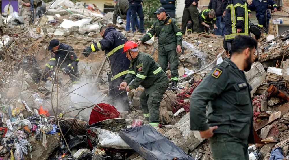 عناصر من الدفاع المدني يرفعون الأنقاض لإنقاذ العالقين تحت مبنيين انهارا في طرابلس شمال لبنان (د.ب.أ)