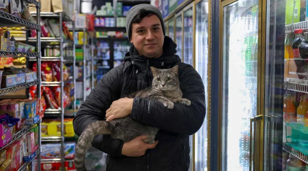Guest Dan Rimada, founder of Bodega Cats of New York holds a cat named Ashley in a bodega corner store on December 17, 2025 in New York City. (AFP)