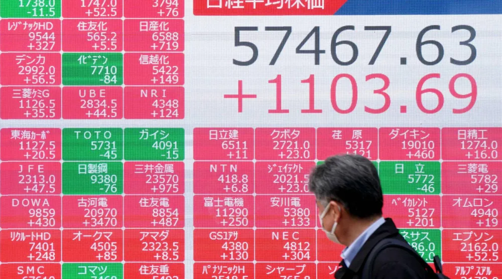 رجل يمر أمام شاشة تعرض حركة الأسهم في وسط العاصمة اليابانية طوكيو (أ.ف.ب)