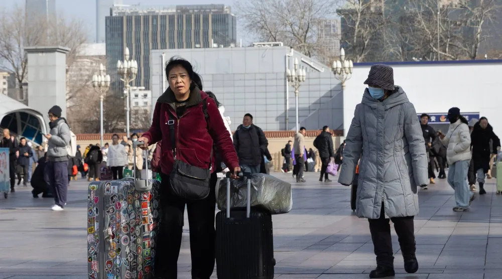 مسافرون خلال فترة أعياد بداية العام الجديد أمام محطة قطارات في العاصمة الصينية بكين (إ.ب.أ)