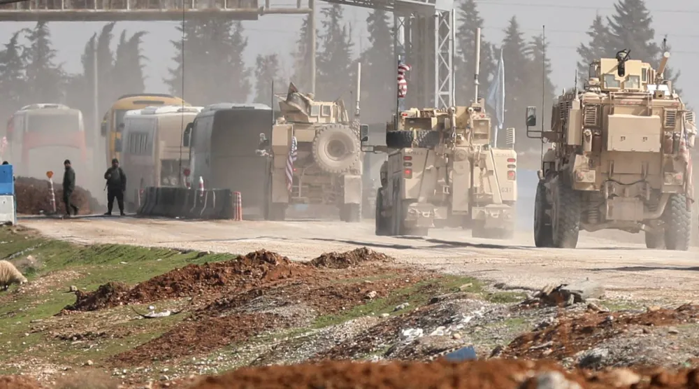 مركبات عسكرية أميركية ترافق حافلات تنقل معتقلي تنظيم «داعش» من سوريا إلى العراق في مدينة القامشلي السورية - 8 فبراير 2026 (رويترز)
