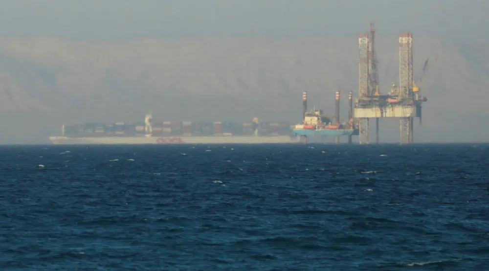 سفينة حاويات تمر بجوار منصة نفطية في خليج السويس (رويترز)