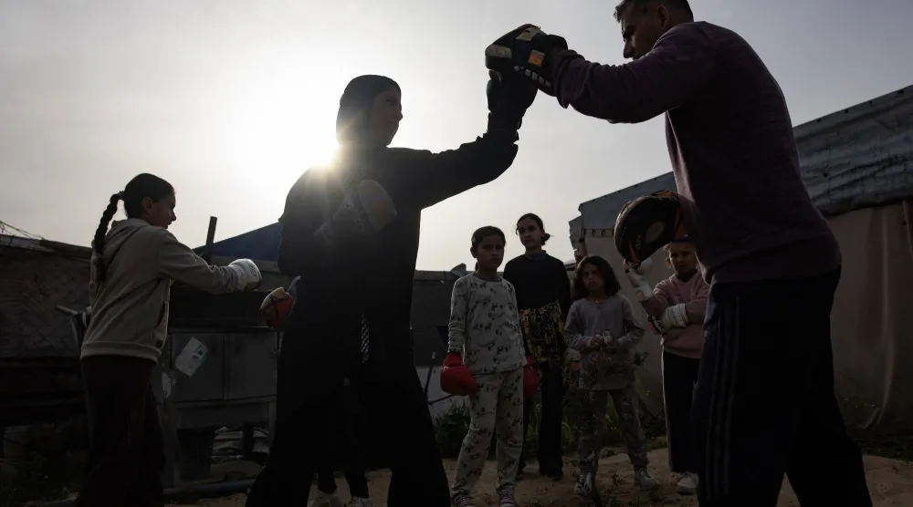 مدرب الملاكمة أسامة أيوب (يمين) يقوم بتدريب فتيات صغيرات داخل خيمة في منطقة المواصي بخان يونس جنوب قطاع غزة (إ.ب.أ)