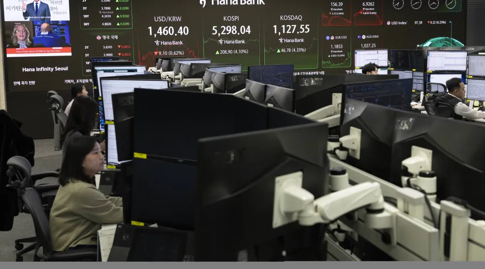 متداولون كوريون جنوبيون يعملون أمام شاشات تعرض مؤشر «كوسبي» ببنك «هانا» في سيول (إ.ب.أ)