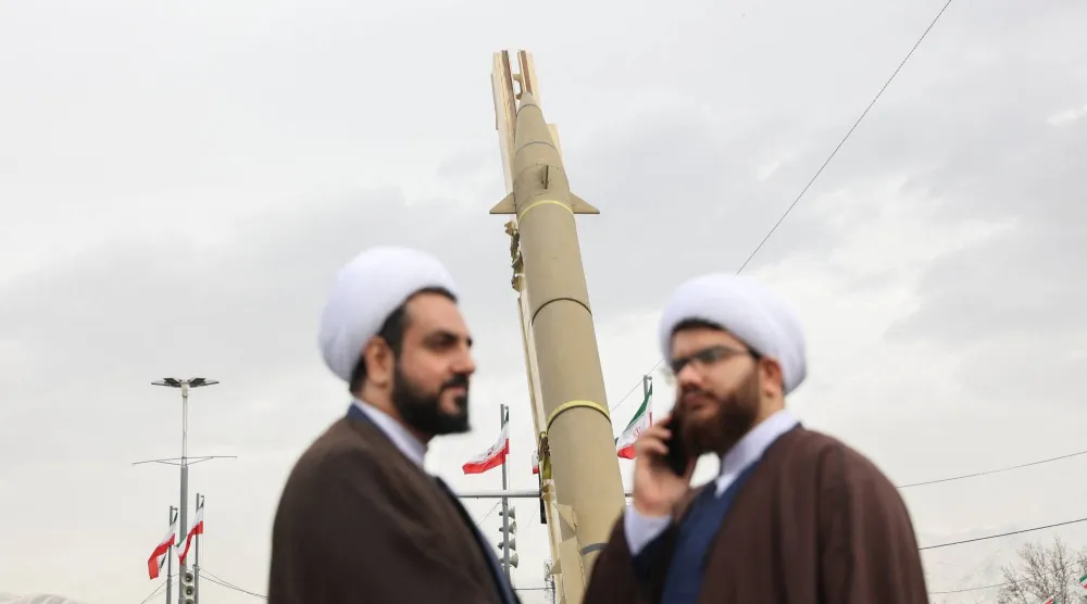 رجلا دين يشاركان في مراسم إحياء ذكرى الثورة بينما يعرض صاروخ باليستي في ميدان آزادي غرب طهران (رويترز)