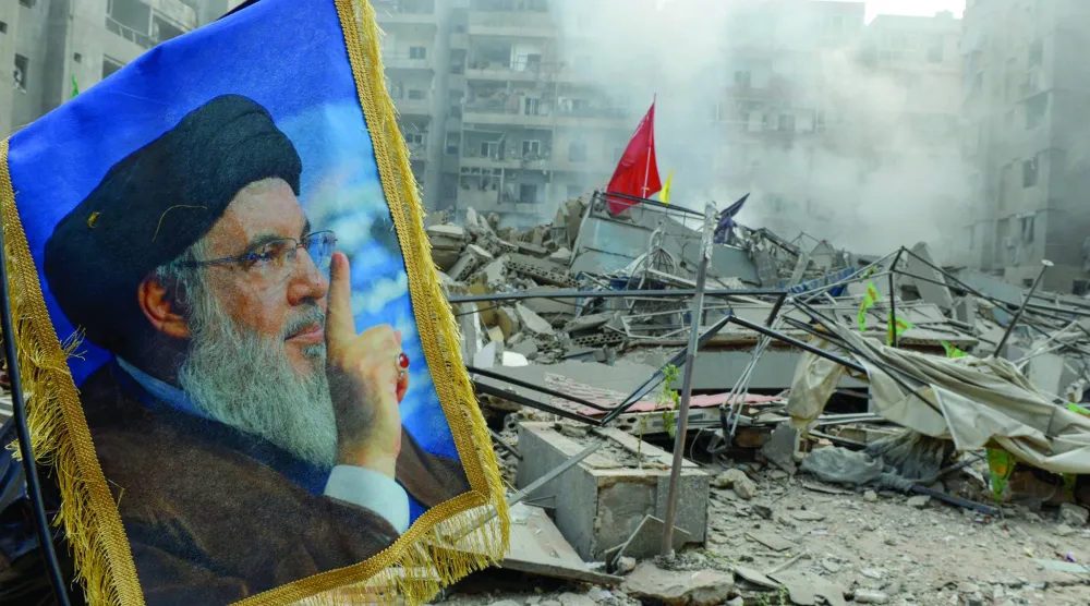صورة لحسن نصر الله أمام أنقاض مبنى دمّره الطيران الإسرائيلي في الضاحية الجنوبية لبيروت (أرشيفية - د.ب.أ)