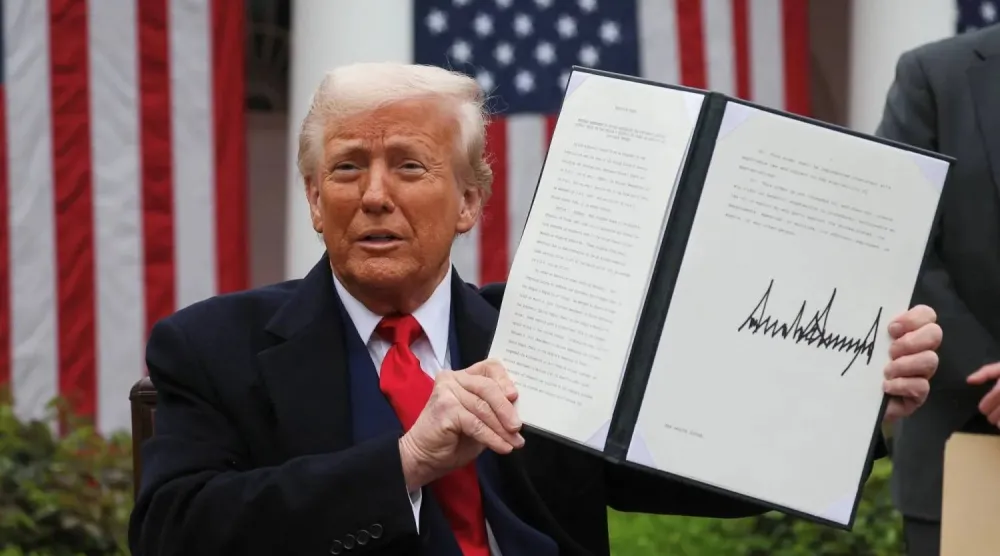 ترمب في حديقة البيت الأبيض يُظهر توقيعه على أمر تنفيذي بفرض رسوم جمركية (رويترز)