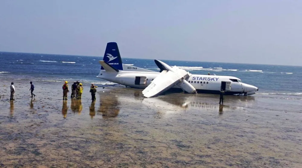 رجال الإنقاذ يقفون بالقرب من طائرة تحطمت على شاطئ البحر في مقديشو بالصومال (رويترز)