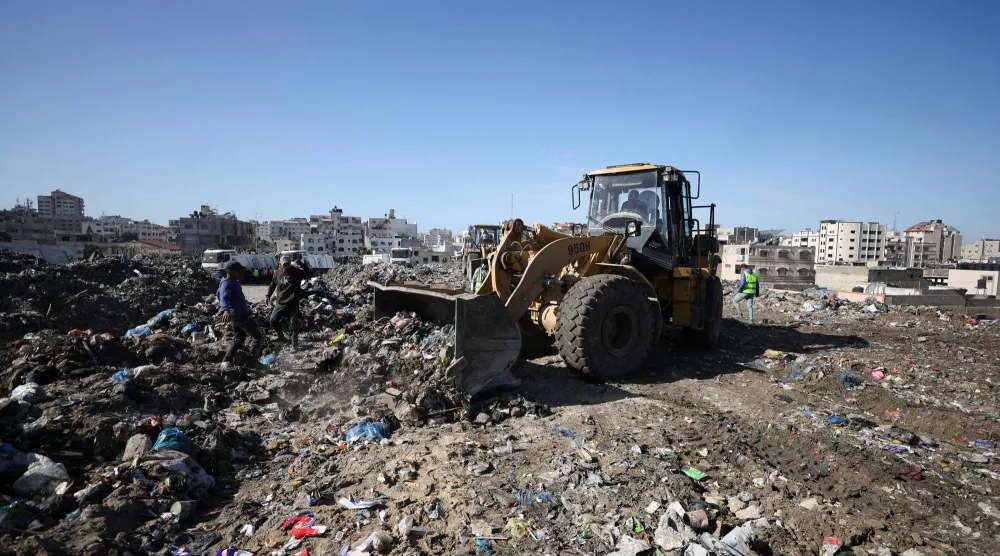 عمّال برنامج الأمم المتحدة الإنمائي بدأوا إزالة النفايات من مكب نفايات ضخم في مدينة غزة (رويترز)