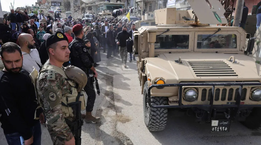 آليات الجيش اللبناني تقوم بتأمين الشارع بينما تجمّع السكان خلال زيارة رئيس الوزراء اللبناني لقرية كفر كلة الجنوبية التي تعرضت لأضرار بالغة إثر القصف الإسرائيلي (أ.ف.ب)